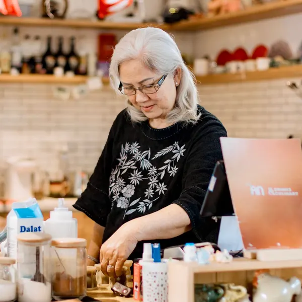 A senior woman packing an order behind the counter of her shop